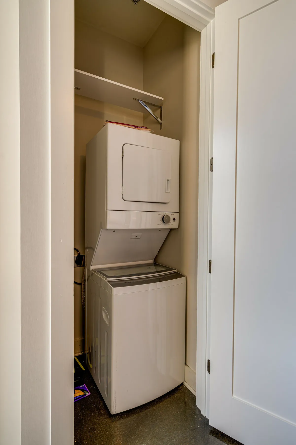 A compact laundry area featuring stacked washer and dryer units with shelves above, emphasizing convenience and practicality for everyday living.